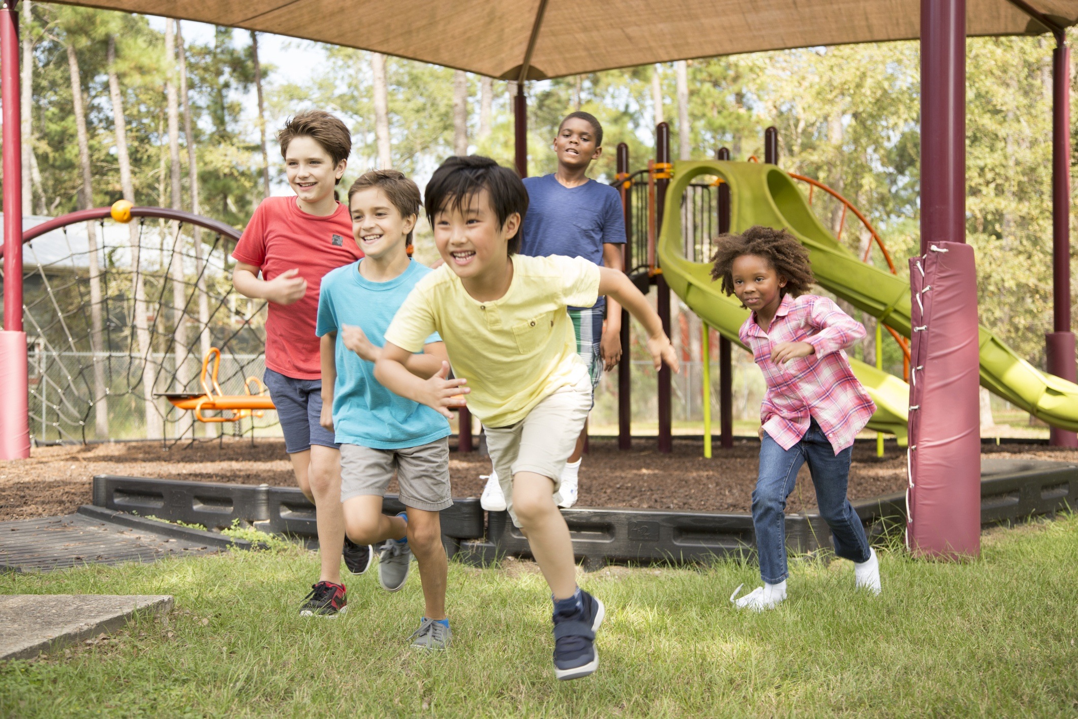 Multi-ethnic group of school children playing on school playground.  The group of friends excitedly run toward the next outdoor activity.  Education in USA, exercise themes.